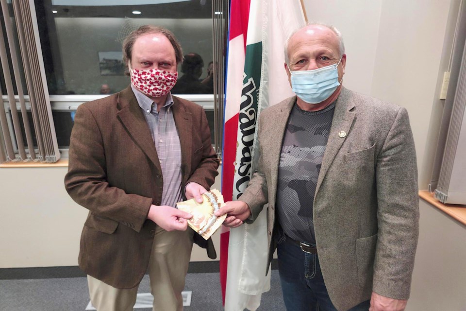 Athabasca University professor Dr. Alex Kondra hands over $7,500 in cash to Athabasca mayor Rob Balay at the Dec. 21 council meeting that will go toward continued efforts by the Keep Athabasca in Athabasca University advocacy group to lobby government officials. 