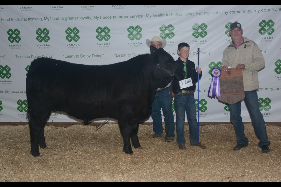 Max Mahar of the Freedom Naples Club with his District Champion Steer “BUD” May 29 at the 59th-annual Barrhead and District 4-H Beef and Sheep Achievement Day show and sale. Behind the steer is beef conformation judge Brent Stewart, while presenting the Pembina Cattle Breeders banner is Brad Yoder. 