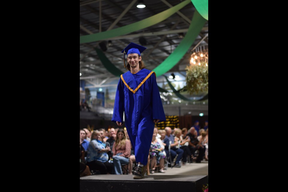 Brent Bombay poses at the top of the stairs as part of the 2023 Grad March.