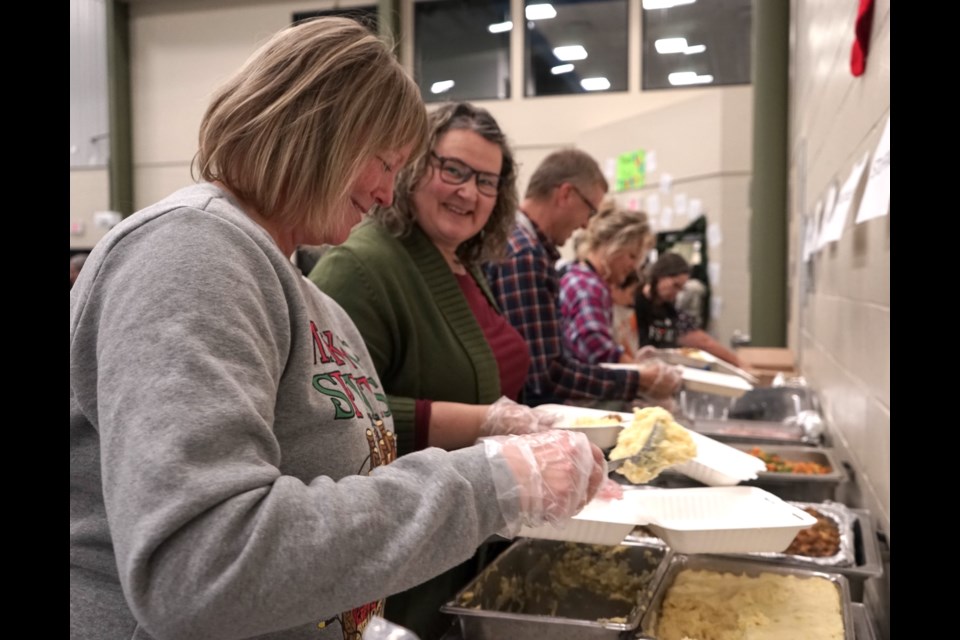 Volunteers like Monica Dahl, left, and Sandra Jardine spent their Thursday afternoon dishing up takeout containers for hungry locals looking to avoid the long lines or enjoy the meal in their own home.                                