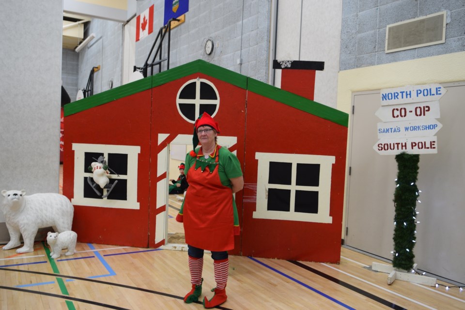 Volunteer elf Joanne Dunbar helps children enter Santa's workshop.