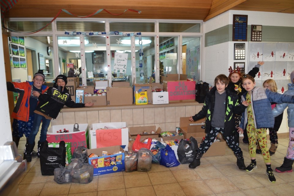 From left to right: From BES' 4A class, Liam, Hayden, Ian, Calli, Brookly and 4B, Christopher  Barrhead Elementary School students Grade 4 students pose in front of food items students and staff collected in the first two weeks of December. The Grade 4 students helped carry the food collection to the waiting FCSS van.