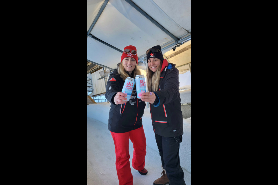 Melissa Lotholz and her regular brakeman for this season Leah Walkeden take time to enjoy a can of Gold Crush non-alcoholic beer. The non-alcoholic beverage is a fundraiser for the pair as is the Team Eh toques they are wearing.