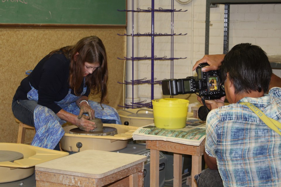 The Athabasca Pottery Club’s workspace was one of the venues visited by ZenSeekers to film their promotional tourism video which encourages visitors to #TakeItToTheLake. Pictured, ZenSeekers photographer Angus Cockney frames a shot of Karen Shaw as she spins a new clay creation. 
Heather Stocking/T&C