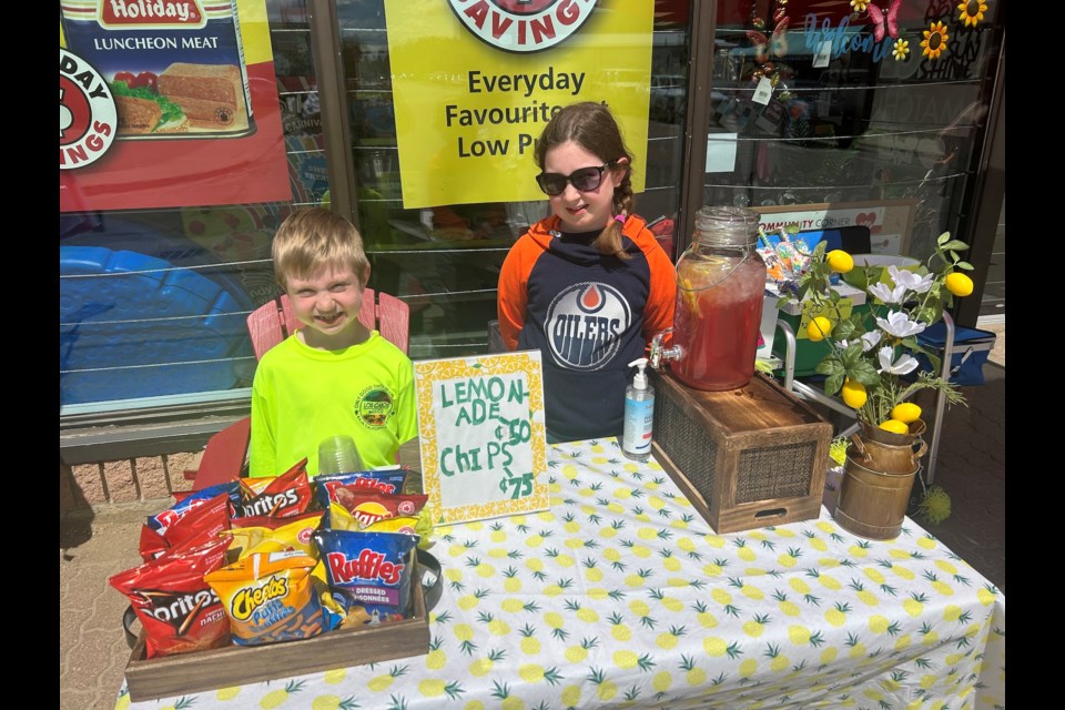 Vaughn and Paige Spargo sell lemonade and bags of chips outside of the Red Apple in Westlock on June 15. The Spargo siblings were among the participants in the annual Lemonade Day event, wherein youth set up lemonade stands for a day in order to learn about operating their own small business; the participants must go through the process of applying for a business license and even budgeting for expenses. 