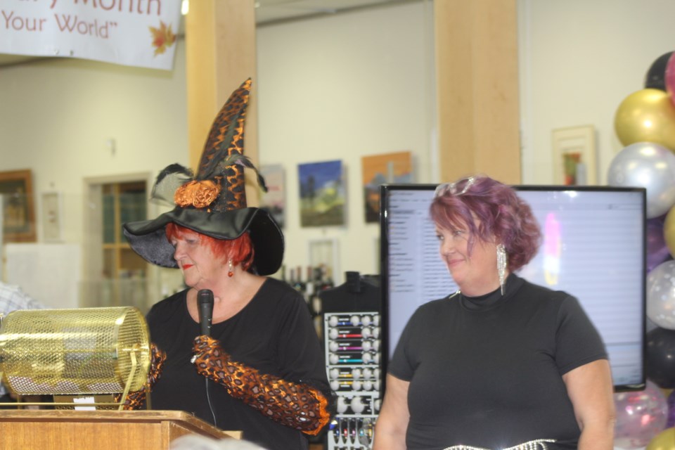 Ruth Bohn (l) and Lori Sagbo (R) lead the crowd through the draws of tickets through-out the Wine O'Clock Somewhere party on Oct. 23.  