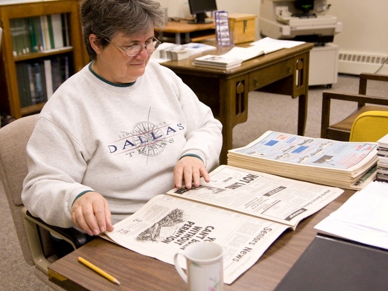 Archives volunteer Linda Doroshenko flips though old newspapers looking for obituaries. She is working on a project to gather and organize all the obituaries from the