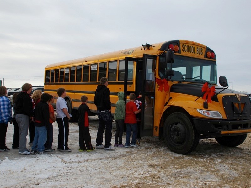 Students at the Boyle School line up around their brand new extracurricular bus, which arrived Wednesday. The new bus will bring students to and from sports and field trips.