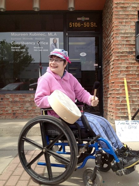 Jill Paquin, 23, smiles as she drums along to the song a group of about 30 individuals sang together to express their concern about recent PDD budget cuts. The rally was held 