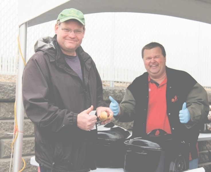 Mark Myerhaug indulges in an early lunch at the Gas Bar Grand Opening on Saturday. The cold winds did not deter locals from stopping by the event while Allan Cote gives a