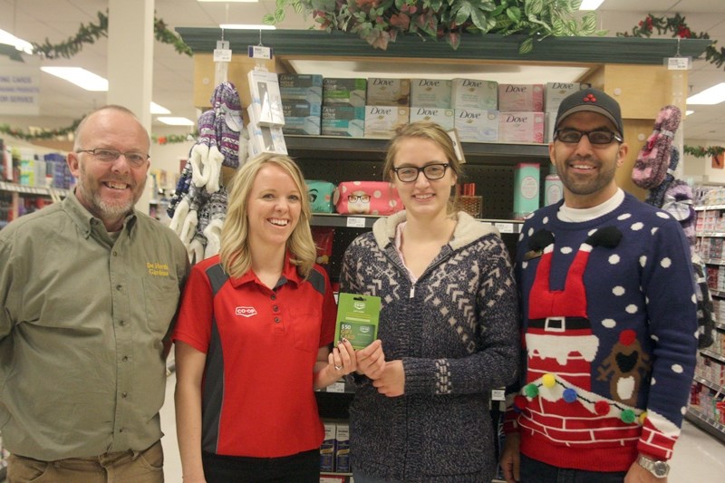 Smiling for the camera, NAIT Interior Design at student Janaye Wierenga accepts a gift card from Pembina West Co-op employee Tracy Grabler. Also pictured are Coen DeHerdt