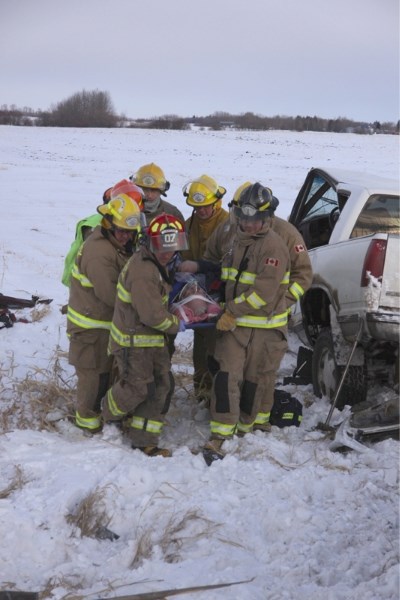 Town of Westlock firefighters help move the patient to a waiting ambulance after a two-vehicle collision northeast of town on Feb. 22.