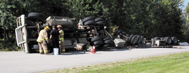 Firefighters survey the scene after this truck rolled over near Fawcett last Wednesday afternoon. Police say the driver, a 53-year-old man from Devon, fell asleep at the