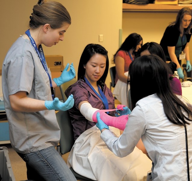 Under the watchful eye of Dr. Magali Benard, U of A student Jenny Hsueh (back to camera) applies a cast to fellow student Esther Jun. In total, 59 medical students were in