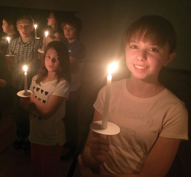 St. Mary School student Camille Williams, at far right, smiles as she holds up a candle during a ceremony on Dec. 15. Each student purchased candles to raise money for the