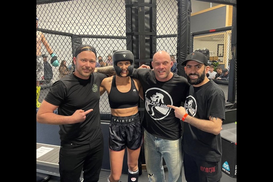 Terell Jonasson, Jamie Verville, coach Josh Kitchen, and Ryan Hamzeh pose for a photo with Verville suited up in protective gear. 