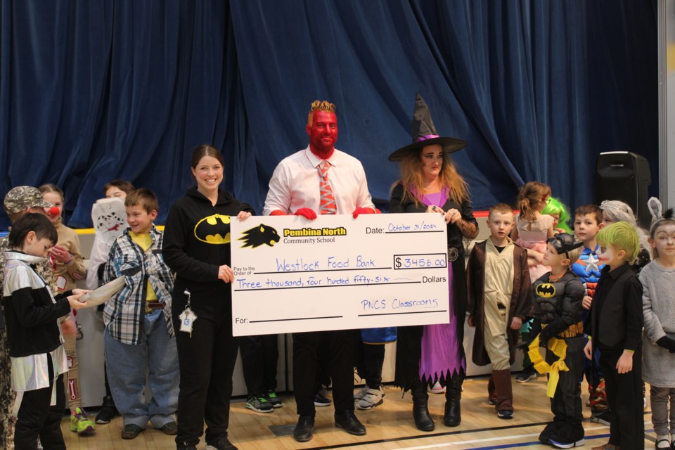 Pembina North Community School staff members holding cheque Jessica Mielke, Mike Ivey, Kim Miller (before getting pied) on Oct. 31.Photo supplied by Jan Borst.