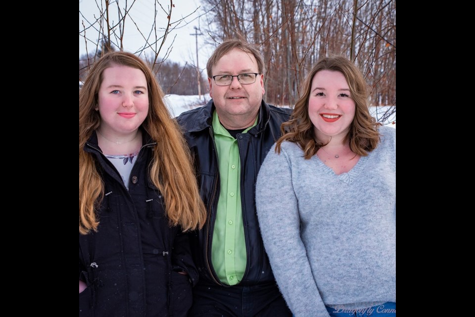 Sarah, Tim, and Jessica McKenna pose for a wintery portrait. Sarah and Jessica remember Tim as a giving, calming presence, and fondly recalled memories of joining him in the theatre as he worked on sets, lighting, and sound for a wide range of productions. Photo from Sarah McKenna's Facebook.