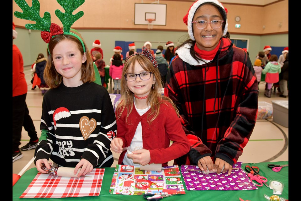 [From left to right] Allison, 8, Grade 4; Evelyn, 9, Grade 4; and Saisha, 10, Grade 5, get ready to stuff the Christmas crackers for seniors during an annual event at Aspenwood Elementary in Port Moody on Nov. 20, 2024.