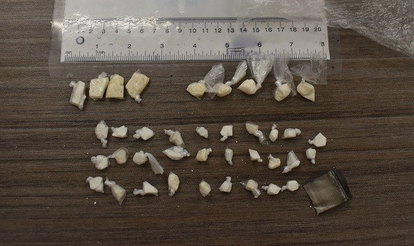 Individually wrapped suspected drugs of various sizes laid out on a table after being seized by police.