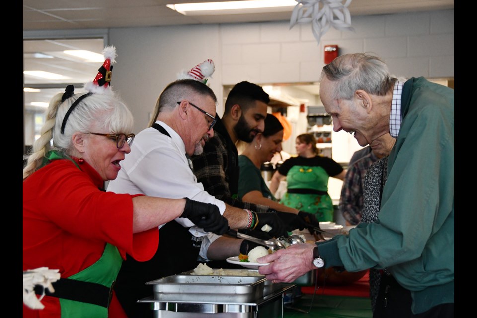 Port Coquitlam city councillors Nancy McCurrach and Glenn Pollock helped to serve a turkey dinner to seniors at the Christmas Luncheon at the Port Coquitlam Community Centre on Dec. 12, 2024.