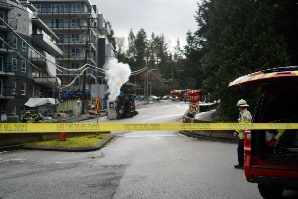 Firefighters stand by as carbon dioxide leaks from several canisters after a commercial truck flipped on Clarke Road Tuesday morning.