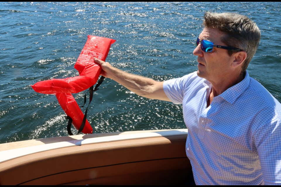 Ryan Sayer, of the Alderside Residents Committee, retrieves a life preserver floating on the waters of Port Moody Inlet.