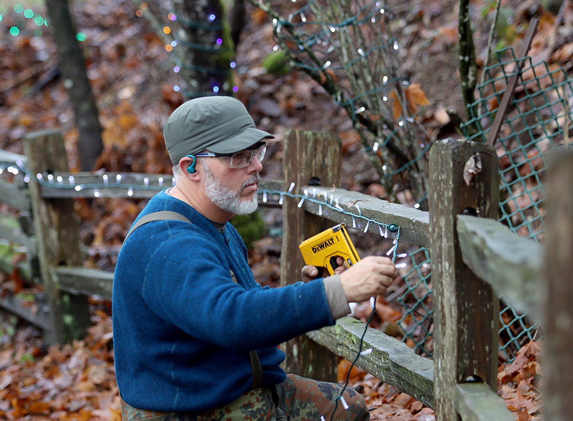 Man affixing lights to fence