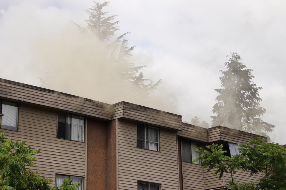 Smoke streams from an aging apartment block on Wilson Avenue in downtown Port Coquitlam on Tuesday.