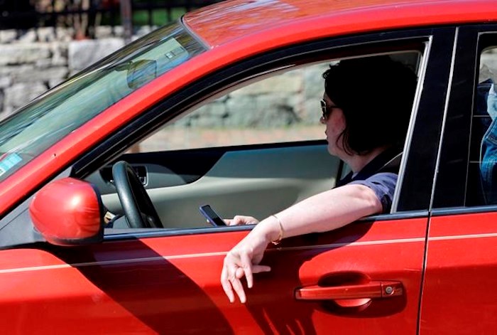  In this Thursday, May 16, 2019 photo, a driver uses his cell phone while driving in Portland, Maine. The son of a 71-year-old senior ticketed for distracted driving says the $368 citation issued to his mother has been cancelled by Vancouver police, and the department has also apologized. THE CANADIAN PRESS/AP-Robert F. Bukaty