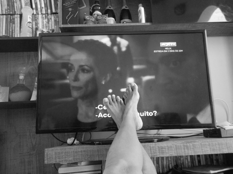 black-and-white-photo-of-feet-propped-up-on-table-with-tv-in-background