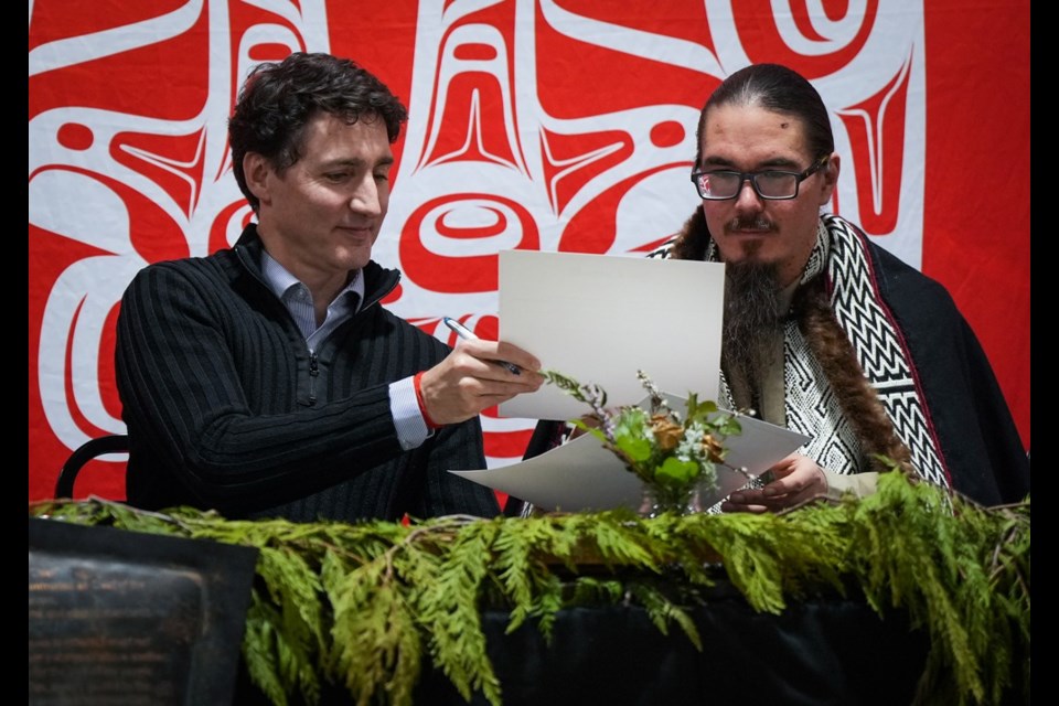 Prime Minister Justin Trudeau and Haida Nation President Gaagwiis Jason Alsop sign documents during a community gathering to celebrate a land title agreement, in Skidegate, B.C., on Haida Gwaii, Monday, Feb. 17, 2025. The federal government will recognize Aboriginal title over the archipelago of Haida Gwaii off British Columbia's northern coast in a historic agreement with the Haida First Nation. The Big Tide Haida Title Lands Agreement affirms that the Haida have Aboriginal title over all of the islands' lands, beds of freshwater bodies, and foreshores to the low-tide mark. THE CANADIAN PRESS/Darryl Dyck