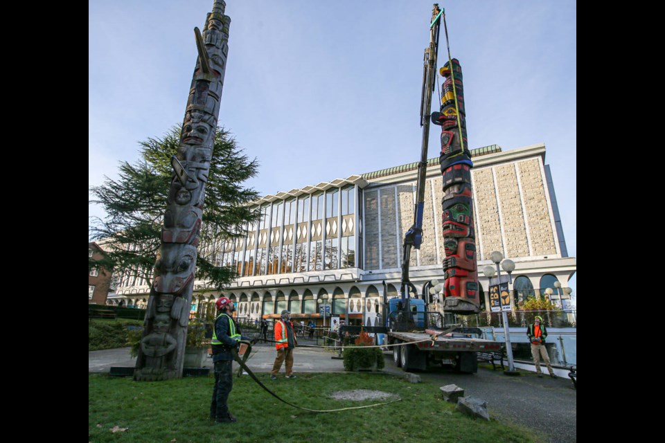 Workers help lift into place master carver Richard Hunt’s totem pole in Thunderbird Park next to Wawadiťła (Mungo Martin House) at the Royal B.C. Museum in Victoria on Monday, Dec. 20, 2021. ADRIAN LAM, TIMES COLONIST