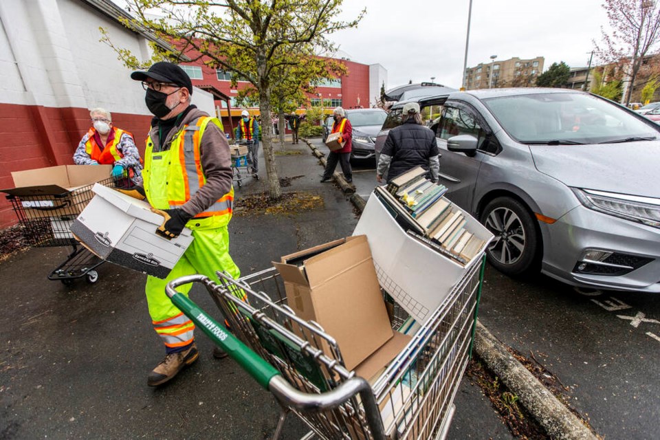 Volunteers unload donated books from cars streaming into the Victoria Curling Club parking lot on Saturday. Drivers are asked to open their trunks and stay in their cars. DARREN STONE, TIMES COLONIST 