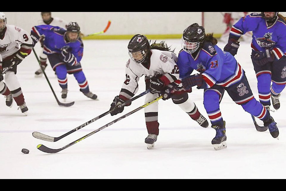 Burnaby Wildcats forward Kylie Cho tries to get away from Victoria Reign defender Emma Narraway during U-15A round-robin action Saturday afternoon at the Victoria Reign Thanksgiving Classic Tournament at Pearkes Arena. The Wildcats prevailed 7-2. The tournament, which also includes U-13A and U-18A divisions, continues today and Monday and it caps the annual World Girls Hockey Weekend.  ADRIAN LAM, TIMES COLONIST 