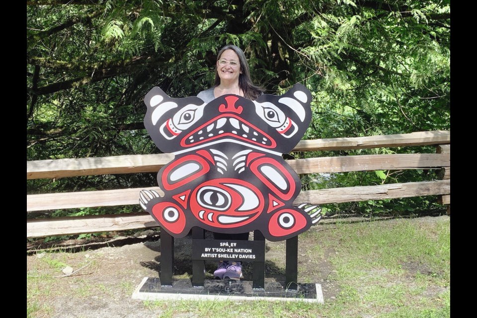 Shelley Davies with her art installation, a bear with a salmon design on its stomach. “The Sooke River is truly a sacred place, and I am humbled to have this design there,” she says. VIA DISTRICT OF SOOKE 