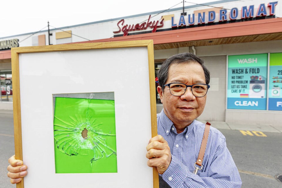 Squeaky’s Laundromat owner Edward Park with a framed bullet hole at Saanich Plaza across from the Bank of Montreal branch at Shelbourne Street and Pear Avenue. DARREN STONE, TIMES COLONIST 