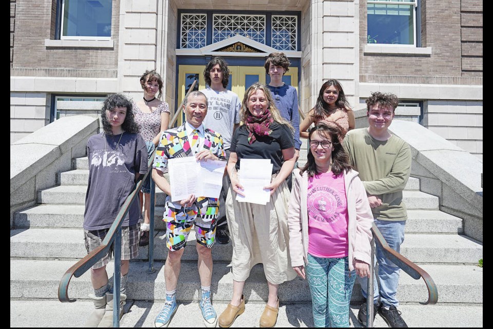 Back row, from left, Lucy Fraser, Lachlan Cholette, Walker Sproule and Leilac Cunanan; front row from left, Cadence Anderson, teachers Dale Sakiyama and Georgina Hope with Eli Thuot with letters and a petitions for solar panels at Vic High. ADRIAN LAM, TIMES COLONIST 