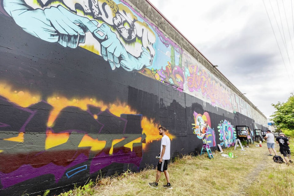 Artist “Blitz works along the E&N Trail between Hereward Road and Lampson Street during the annual Trackside Paint Jam in Victoria on Saturday. The half-kilometre Trackside Art Gallery along the trail is known as Canada’s largest legal graffiti wall. The artwork isn’t here to stay. Artists frequently paint over the walls with new pieces popping up all the time. DARREN STONE, TIMES COLONIST 