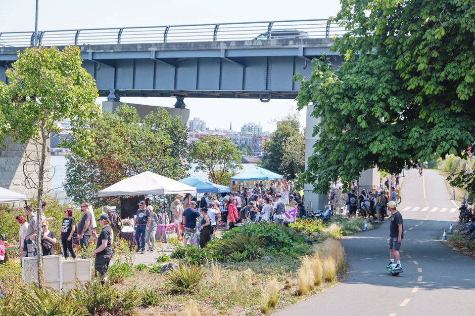 People gather under the Bay Street Bridge next to the Galloping Goose Trail for an eclectic community art show on Saturday.	TIMES COLONIST 