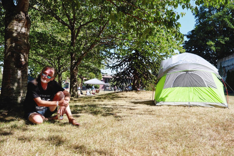 Michael Delday, 69, sits beside a tree in Irving Park on August 3, 2024. Campers are refusing to leave after city banned sheltering in the park on Thursday. TIMES COLONIST 