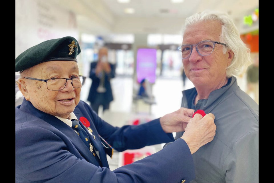 Gordon Quan pins a poppy on Steven Allaire at Mayfair shopping centre on Friday during Quan’s annual campaign for his Royal 
Canadian Legion Branch, Britannia No. 7. TIMES COLONIST 