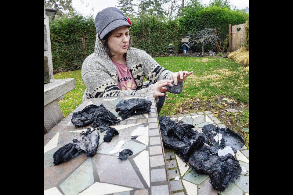 Carey Road resident Sarah Wakefield with chunks of debris that were blown into her yard from a massive fire on Quadra Street early Wednesday. DARREN STONE, TIMES COLONIST 