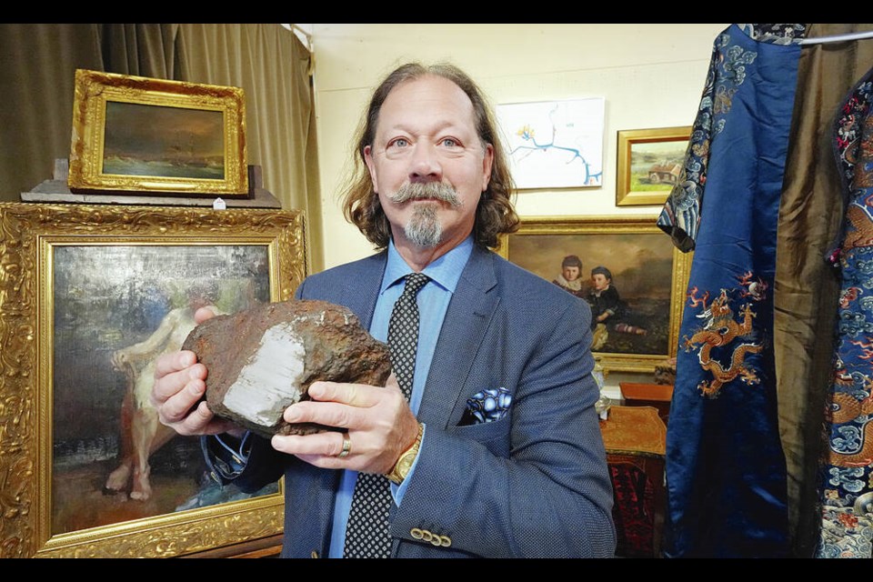 Peter Boyle, president of Lunds Auctioneers & Appraisers, holds a bowling-ball size meteorite coming up for auction on Dec. 10. ADRIAN LAM, TIMES COLONIST 