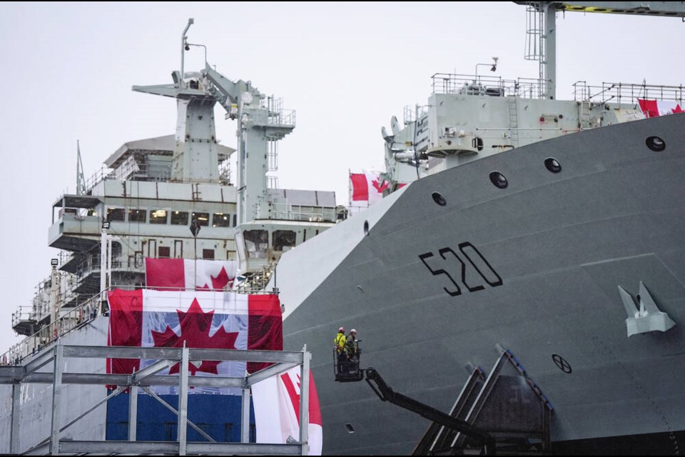 Workers are seen on a lift beside the new Royal Canadian Navy Joint Support vessel before a launch and naming ceremony at Seaspan Shipyards, in North Vancouver, saʴý, on Friday, December 13, 2024. The ship is scheduled to be delivered to the Royal Canadian Navy in 2025. THE CANADIAN PRESS/Darryl Dyck