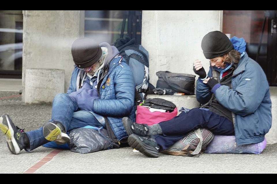 Two people sit on the sidewalk on Pandora Avenue in front of the McPherson Theatre last week. Starting last September, saʴý Housing and the city contracted outreach workers employed by Pacifica Housing to try and connect with people living on the block with the intent of getting them off the streets and into shelter beds. ADRIAN LAM, TIMES COLONIST 